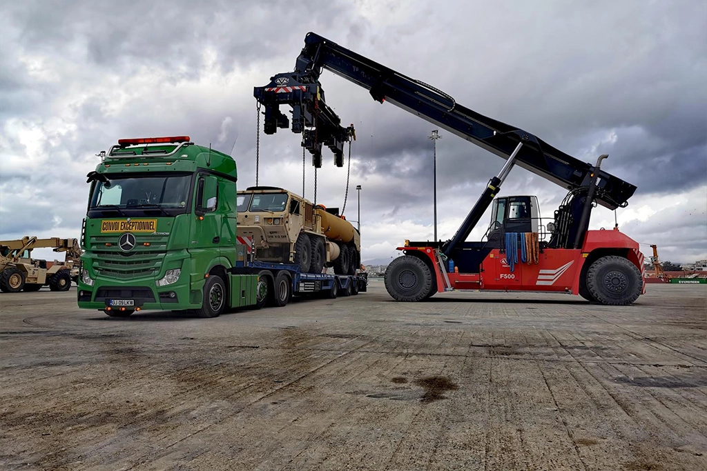 Ansamblu din flota Ansian si un utilaj ce urmeaza sa fie descarcat de pe semi-trailer