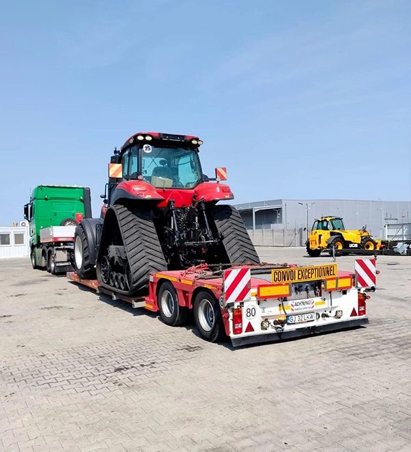 Semi-trailer incarcat cu un utilaj agricol pregatit pentru a fi dus la destinatie